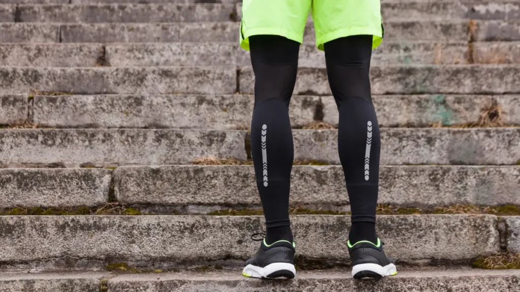 Person wearing black compression sleeves on calves to support vein health and manage chronic venous insufficiency during a walk.