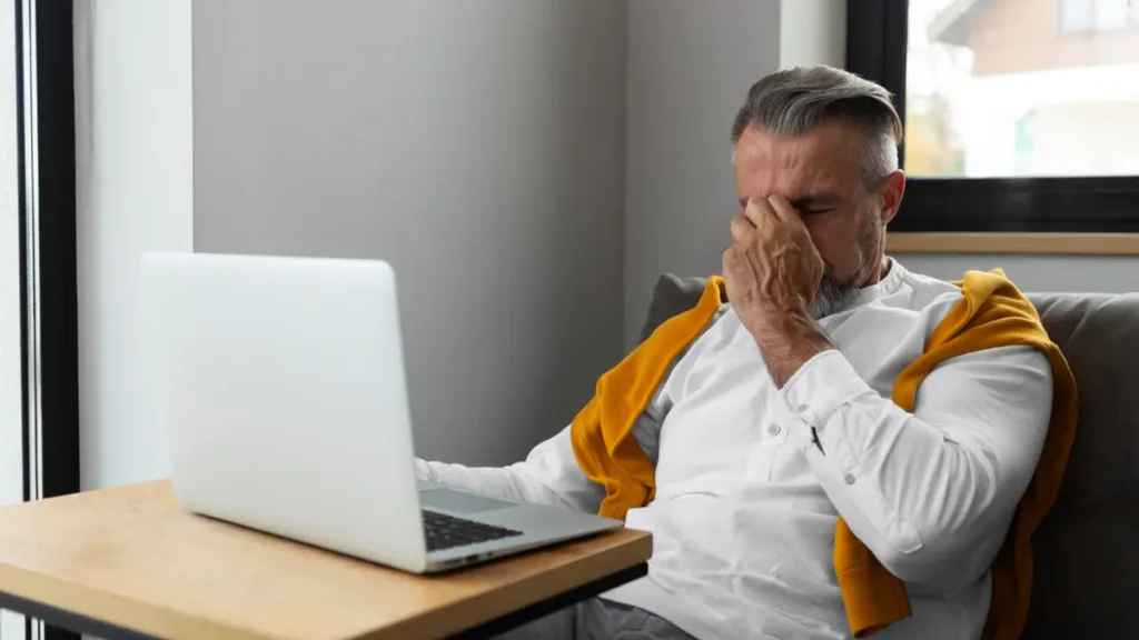 Mature man sitting at a desk to illustrate how prolonged sitting leads to adaptive shortening of hip flexors.
