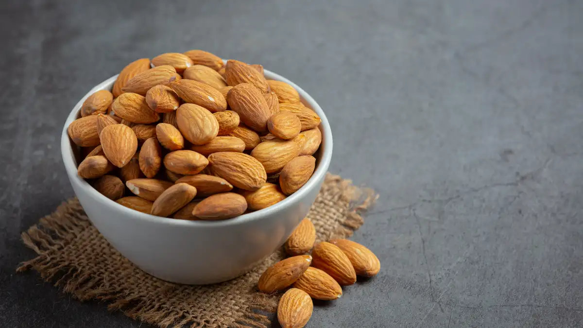 Healthy snack of raw almonds in a white bowl, providing a natural source of fiber and protein for stable energy levels.