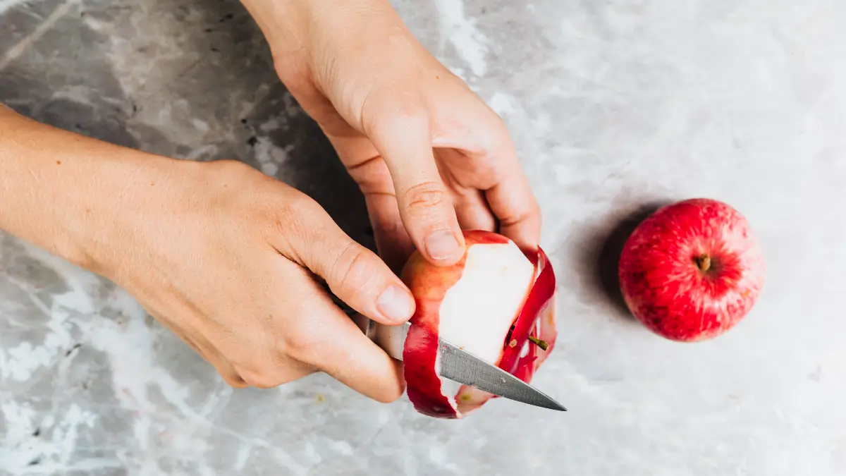 Fresh red apple being prepared on a marble countertop, a high-fiber fruit snack for sustained energy.