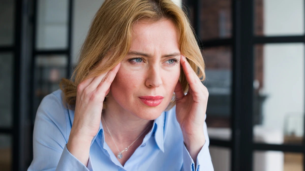 Mature woman touching her temple while struggling with brain fog to improve ATP cellular energy