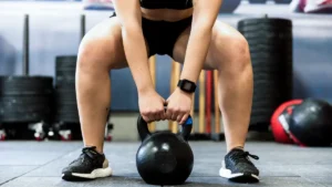 Close up of a person performing a kettlebell squat to create the mechanical tension needed for bone building.