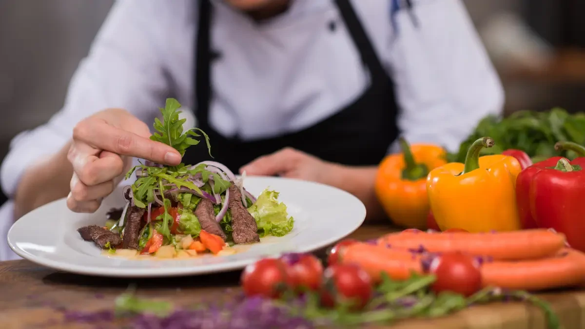 Chef garnishing a protein-rich meal to demonstrate how to build a plate around an anchor source for optimized cortisol management.