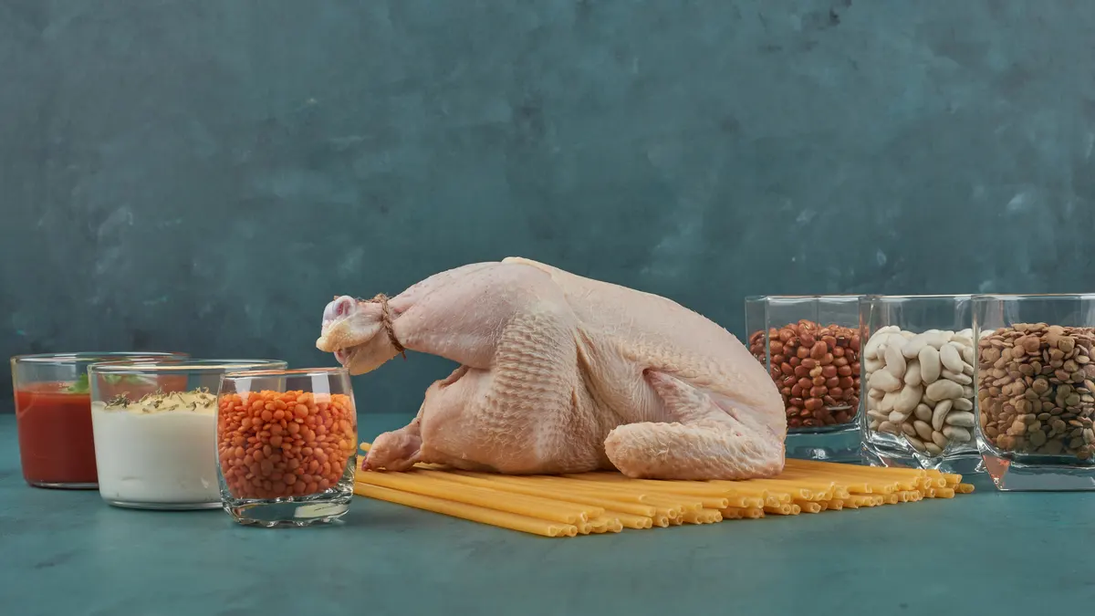 Assorted high-leucine protein sources including whole chicken, lentils, and beans to help seniors hit the mealtime leucine threshold.