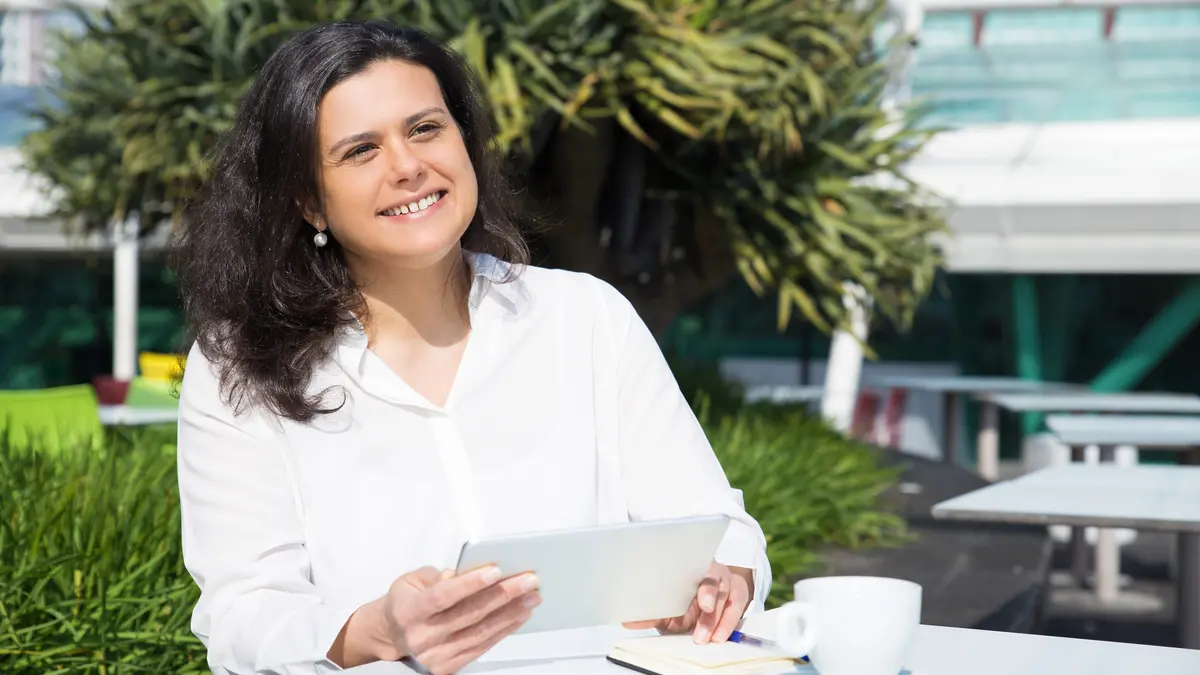 Confident mature woman sitting comfortably at an outdoor cafe to represent the freedom and active lifestyle found through effective pelvic floor health management.