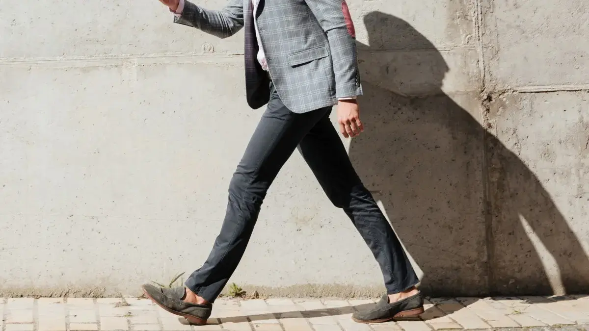 Side view of a person overstriding while walking to illustrate how landing the foot too far forward disrupts core stability and breathing rhythm.