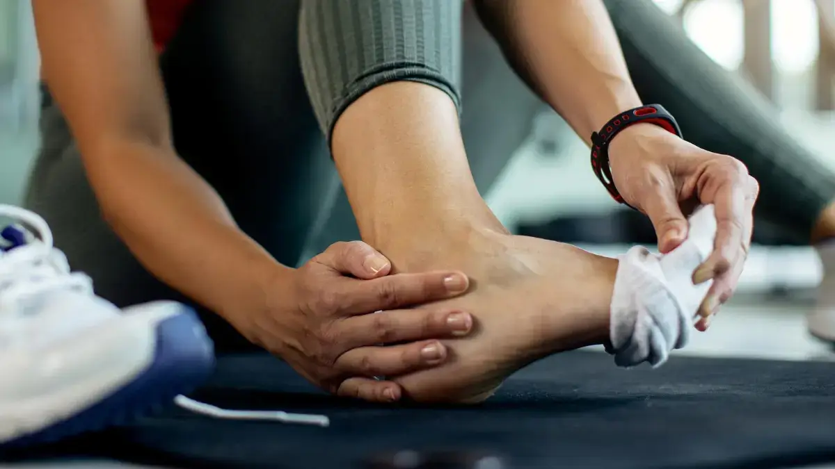 Close up of a person checking their ankle for swelling before performing metabolic heat production exercises like ankle circles and foot flexing.