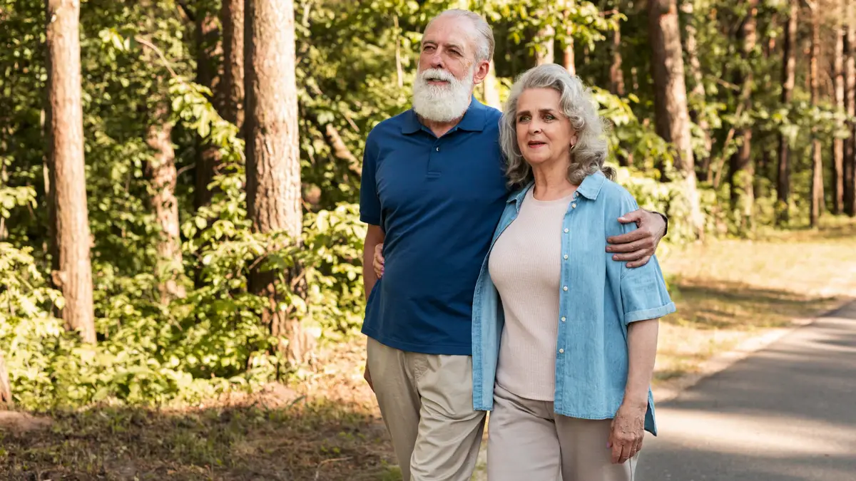 Mature couple practicing upright posture to support basal metabolic rate while walking outdoors.