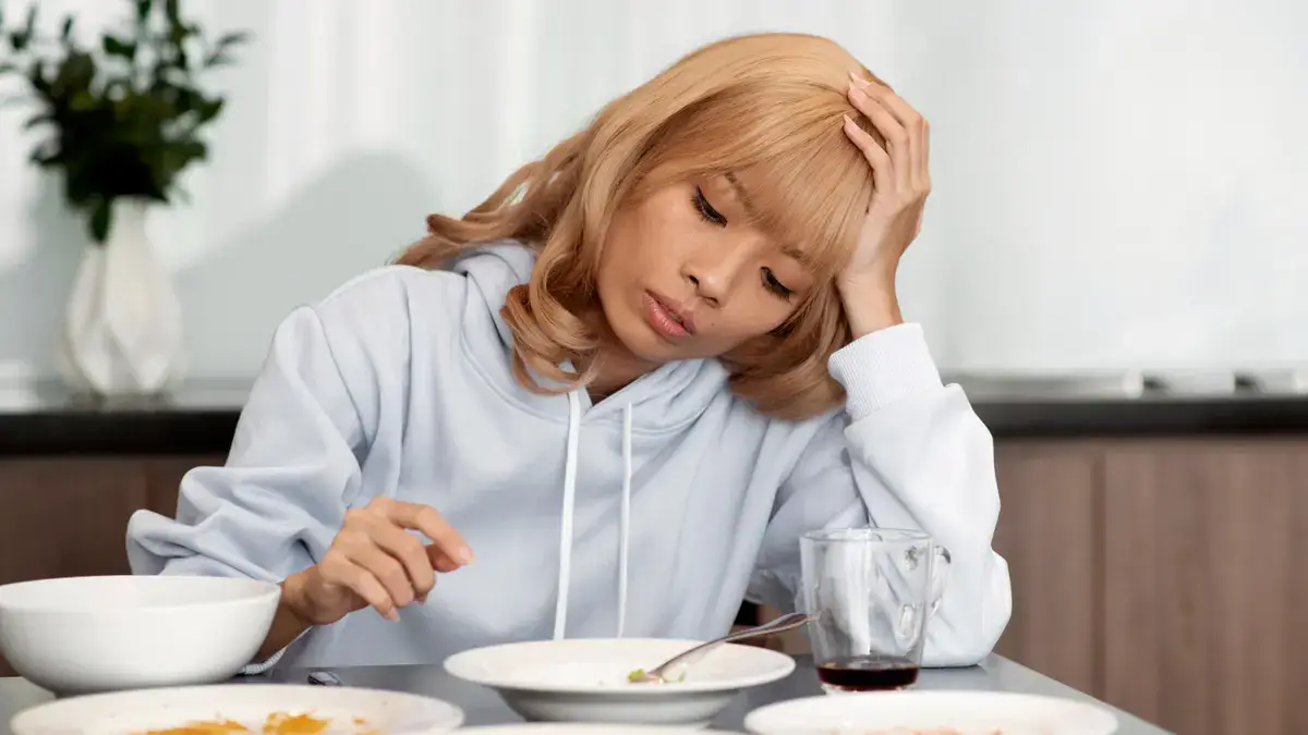 Mature woman looking fatigued after a meal due to low ATP cellular energy and inadequate protein intake.