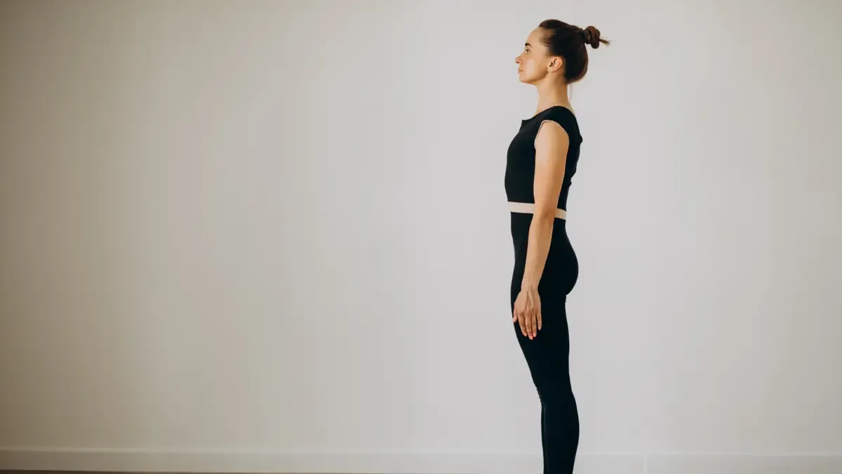 Side profile of a woman demonstrating neutral standing posture with the head aligned over the shoulders to create vertical space for lung expansion.
