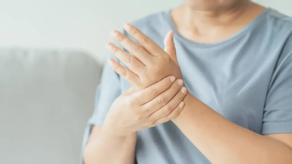 Mature woman of South Asian descent holding her wrist to soothe numbness and tingling associated with carpal tunnel inflammation.
