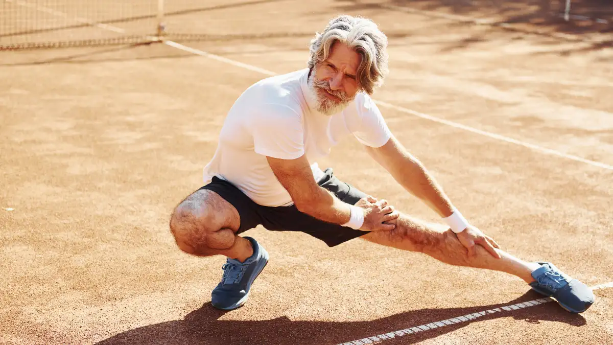 Mature man in athletic wear performing a mobility check to improve ankle dorsiflexion mobility for long-term knee health.
