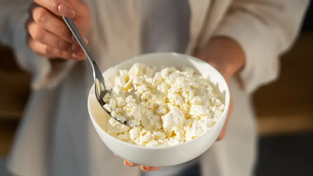 Woman holding a bowl of cottage cheese to reach the leucine threshold required for muscle protein synthesis after 50.