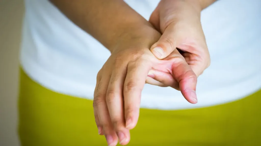 Close-up of mature hands pressing a spongy, swollen knuckle to check for synovitis and whole body inflammatory signals.