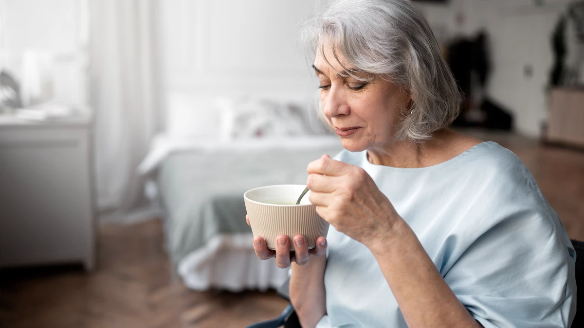 Mature woman holding a bowl of Greek yogurt to provide slow-release casein protein for overnight muscle protein synthesis.