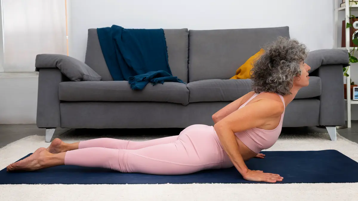 Active woman in her 60s practicing postural elongation on a mat to improve pelvic floor muscle strength and reduce incontinence symptoms.
