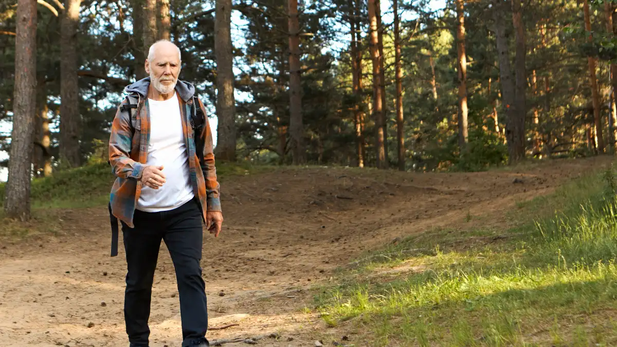 Mature man walking across a gravel driveway to challenge his proprioceptive sensors and maintain balance after 50.