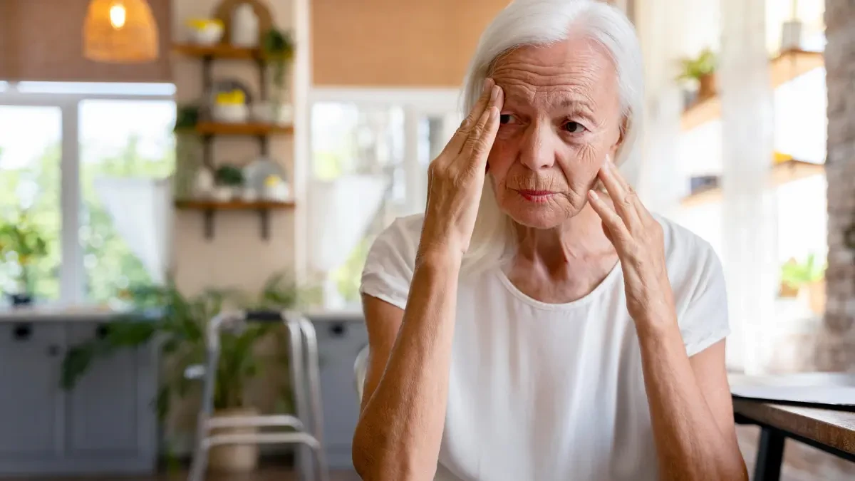 Mature woman in her 60s looking concerned at home, demonstrating the reflective state of monitoring breathing patterns and health warning signs.