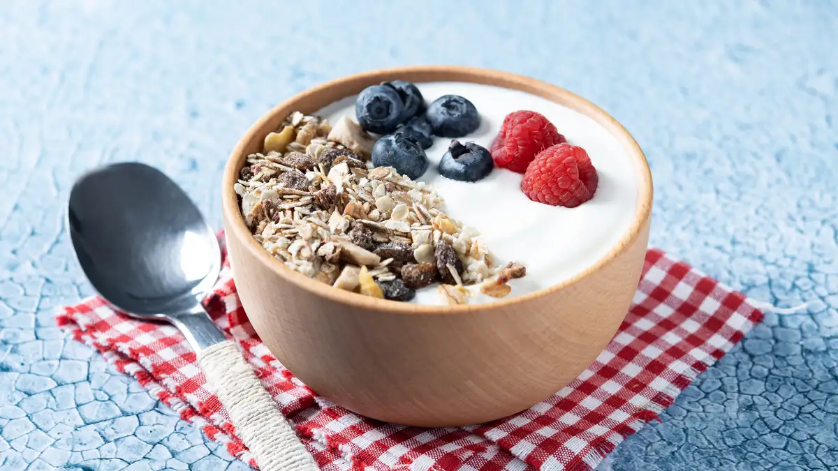 A high-protein Greek yogurt bowl topped with muesli and fresh berries to support muscle protein synthesis at breakfast.