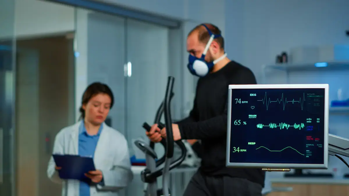 Patient undergoing a clinical VO2 max treadmill test with oxygen mask and heart rate monitors to track cardiovascular performance.
