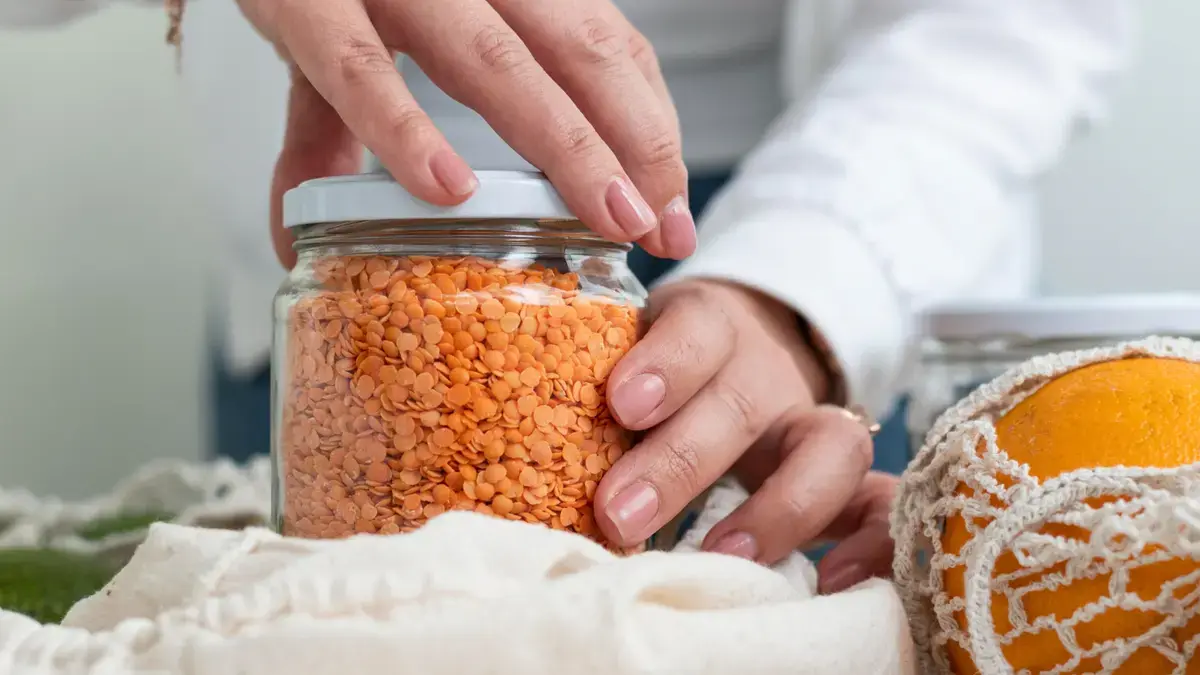 Mature woman's hands gripping a glass jar lid with effort to illustrate early signs of sarcopenia and age-related strength decline.