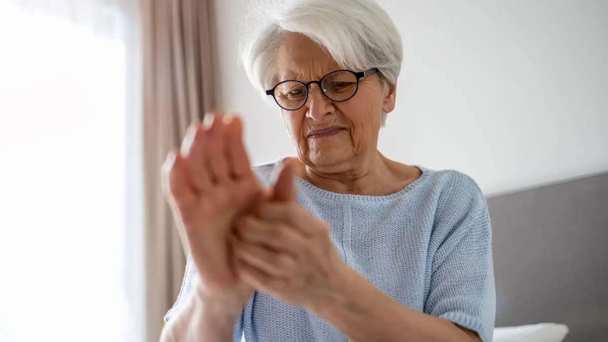Mature woman rubbing her palm to address nerve-related tingling caused by the methyl folate trap masking a B12 deficiency