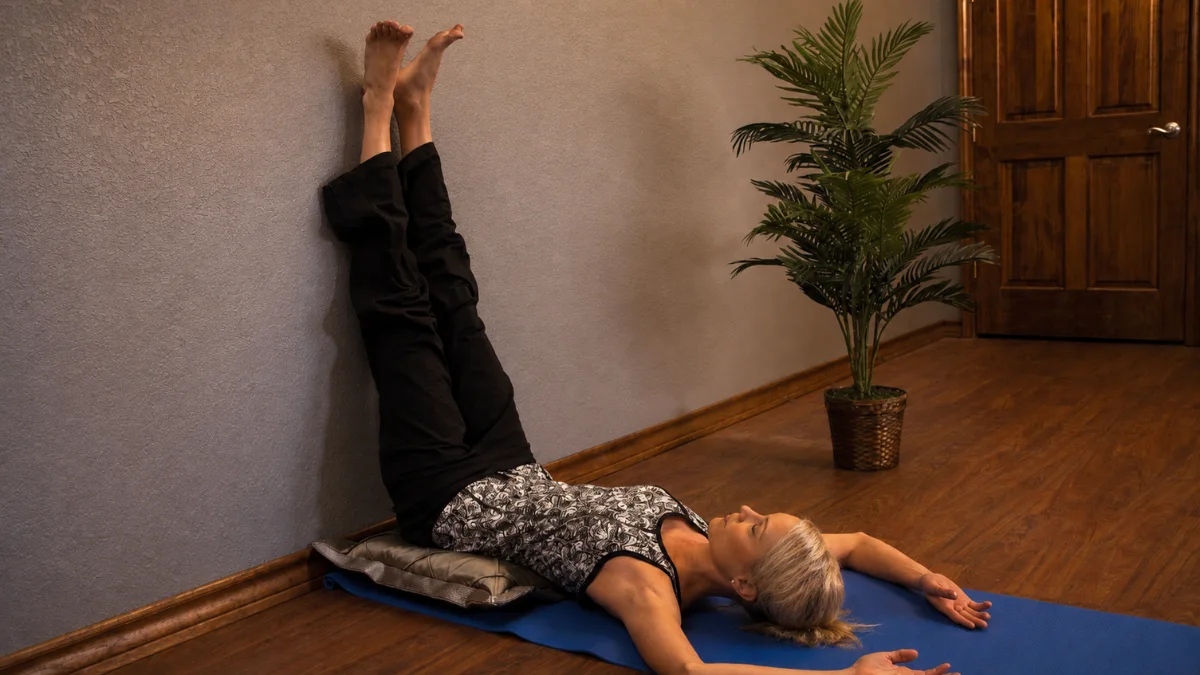 Mature woman practicing legs up the wall benefits for seniors to naturally reduce end-of-day ankle swelling.