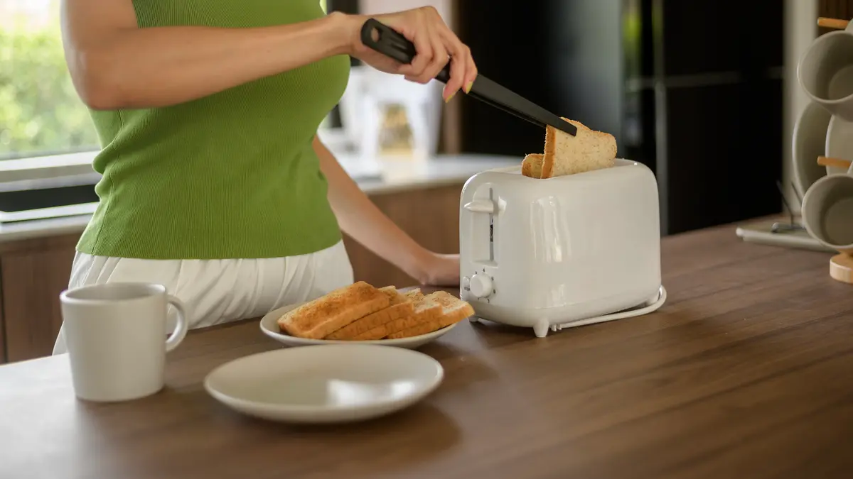 Woman toasting sprouted grain bread to improve digestibility and support a healthy basal metabolic rate.
