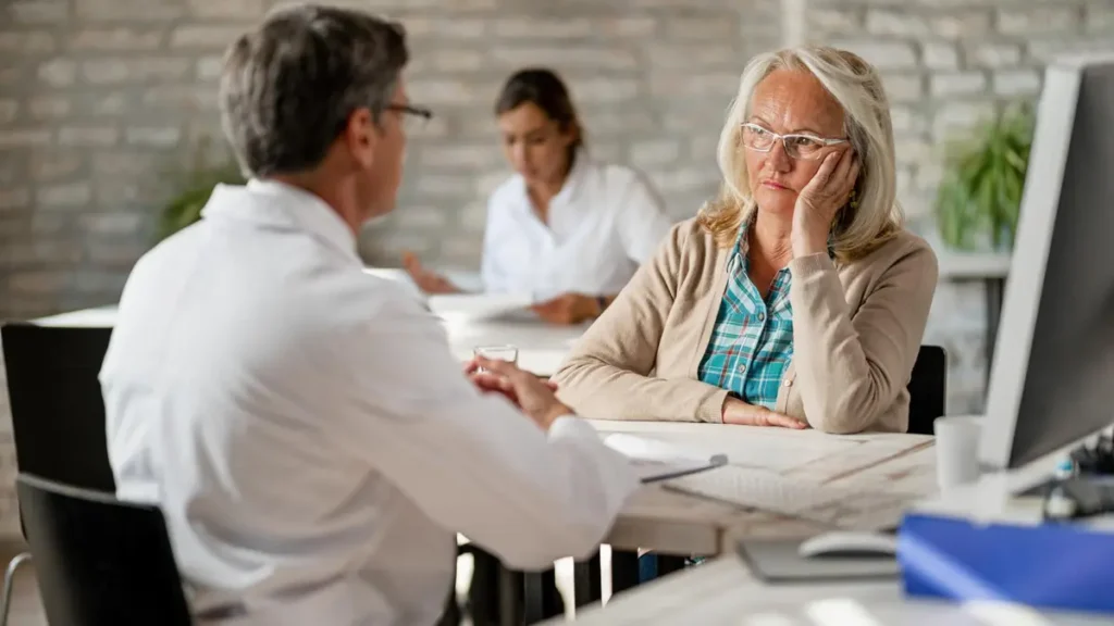 Older woman with sleep problems consulting a doctor about insomnia and melatonin after 50, seeking professional sleep disorder diagnosis.
