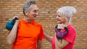 Active mature couple in their 60s holding kettlebells to support metabolic heat production and build muscle mass after 50.