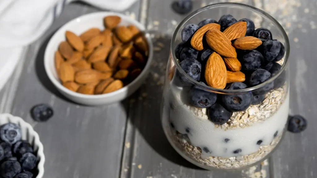 Greek yogurt parfait with blueberries and almonds in a glass jar showing how to pair fruit with protein to reduce blood sugar spikes.