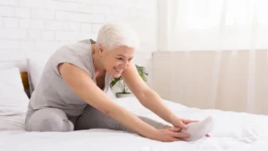 Senior woman smiling while stretching on bed in the morning showing easy home activation routine for adults over 50
