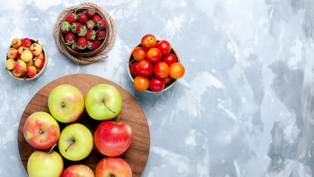 Fresh low glycemic index fruits including apples cherries and strawberries arranged in bowls as smart choices for blood sugar control.