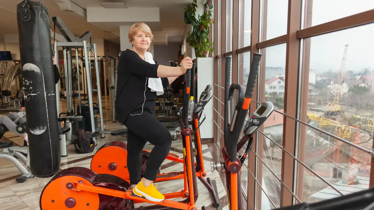 Mature woman using an elliptical trainer at a conversational pace to support cortisol management and metabolic health.