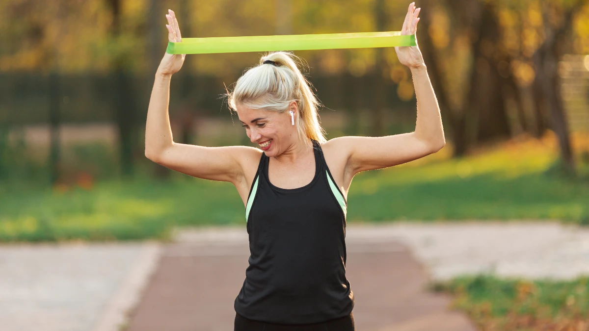 Active mature woman using a resistance band to stimulate metabolic heat production and preserve muscle mass during a fasting cycle.