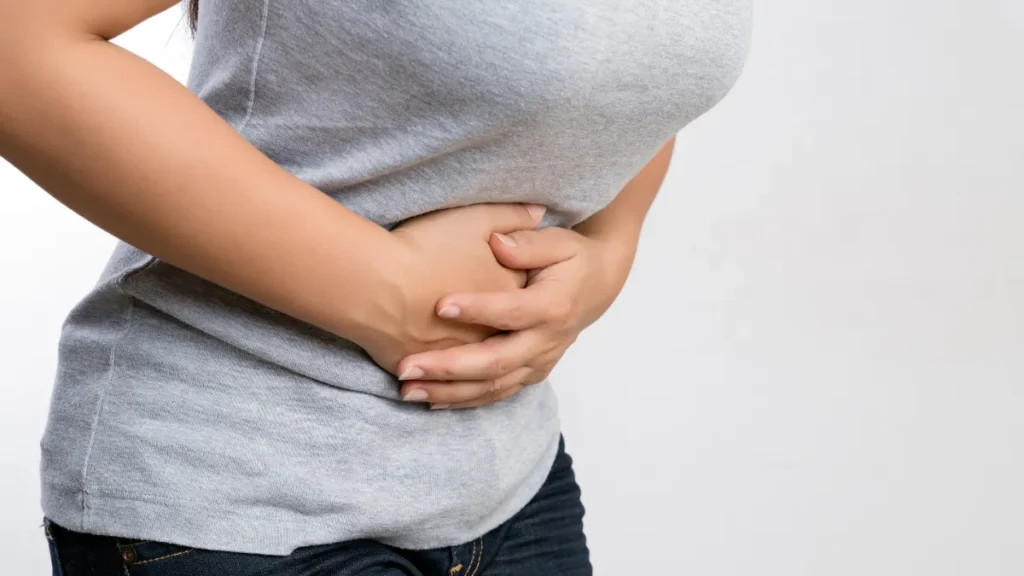 Woman clutching her abdomen with both hands, experiencing persistent gut discomfort caused by digestive dysfunction and low stomach acid.