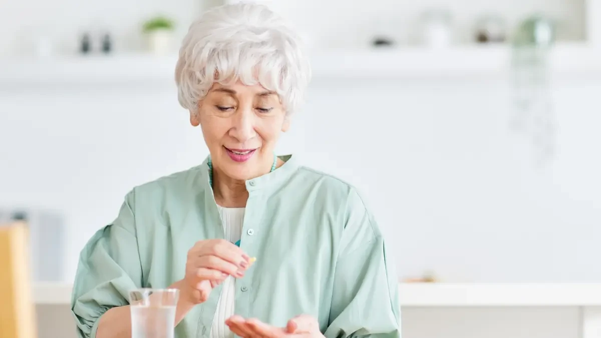 Mature woman taking a Vitamin D3 supplement to support ATP cellular energy and slow the biological aging process.