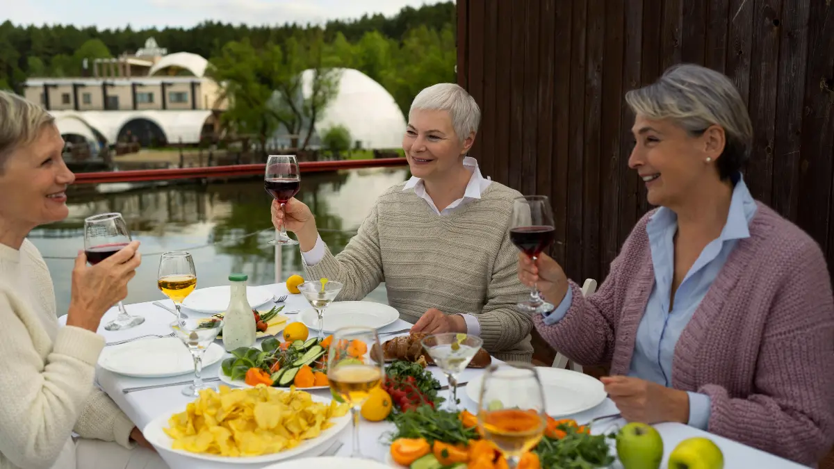 A group of senior women enjoying a social community meal outdoors, highlighting the benefits of local senior meal programs for nutrition and connection.