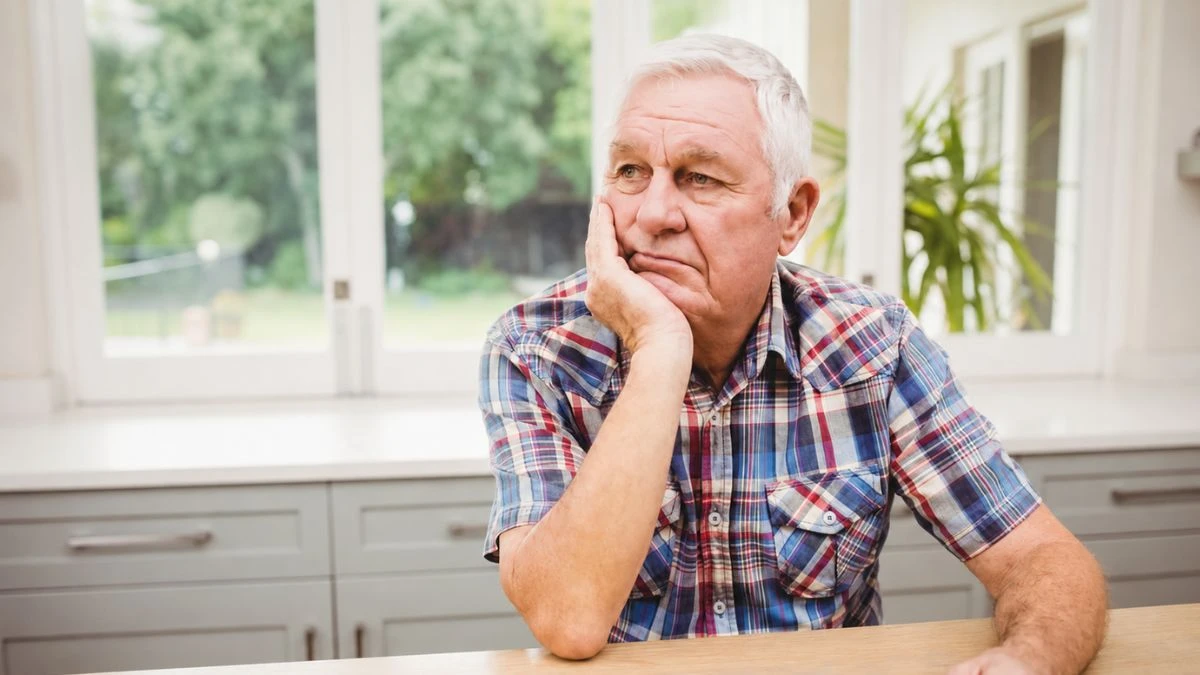 Older man experiencing sleep problems from low testosterone sitting alone looking tired and fatigued.