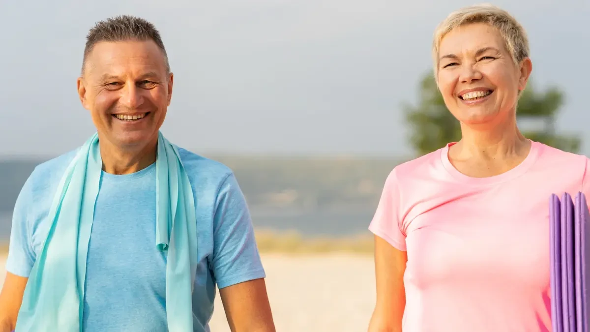 Smiling couple over 50 in athletic wear outdoors, representing healthy lifestyle choices to manage high uric acid and metabolic health.