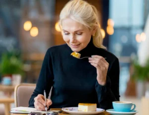 Mature woman tracking her feeding window in a planner to manage insulin resistance and metabolic health after 50.