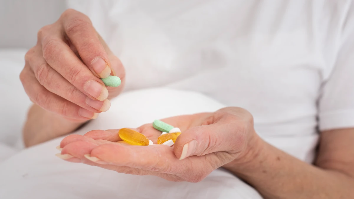 Mature hands sort through a handful of large, colorful vitamin capsules to monitor hidden dietary triggers for calcium oxalate stones.