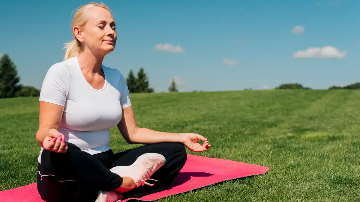 Mature woman practicing mindful breathing on a yoga mat to support cortisol management and optimize metabolic health after 50.