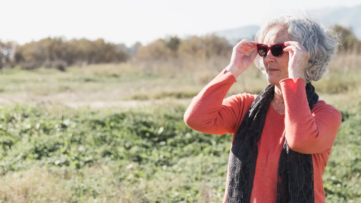 Older woman putting on sunglasses outdoors in morning light illustrating how early sun exposure resets your circadian clock.