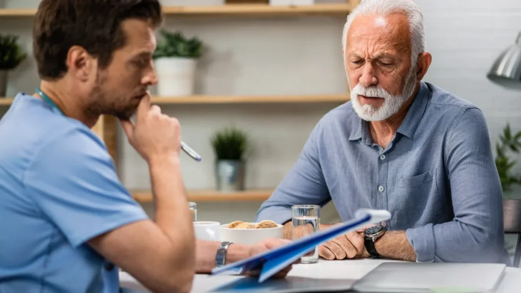An older man reviews medical reports with his doctor during a clinic consultation to discuss symptoms.