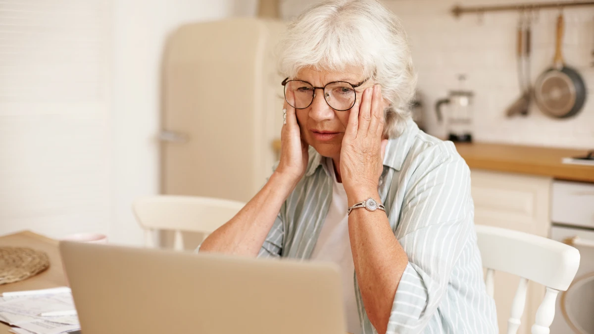 Mature woman experiencing brain fog after 50 while trying to focus on her laptop in a home office.