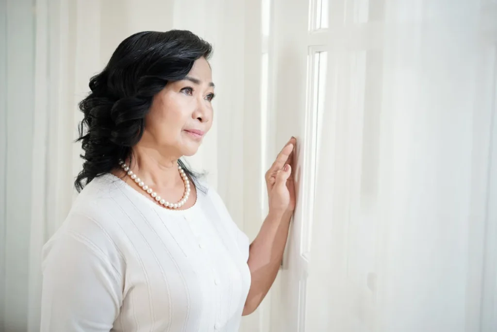 "mature woman looking out window pensive.