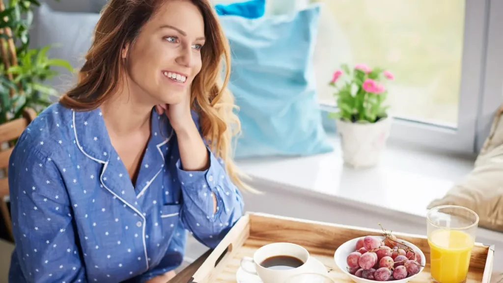 Woman in pajamas enjoying a light morning breakfast after an overnight fast, illustrating a 12-to-14-hour fasting window for health