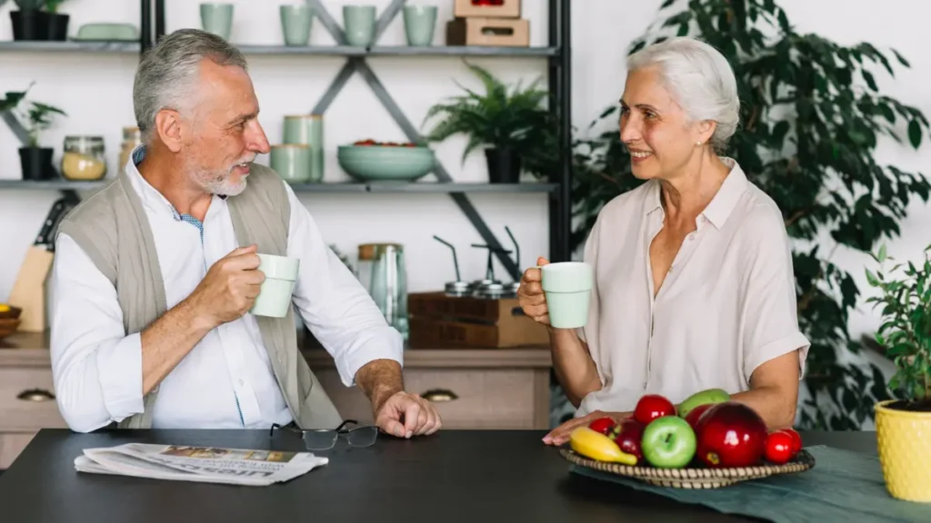 Mature couple drinking herbal tea together in a bright kitchen, adopting healthy evening habits to preserve optimal REM sleep.