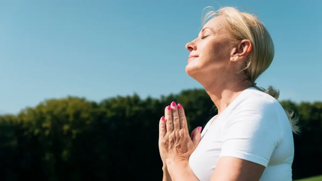 Vibrant mature woman breathing deeply in morning sunlight, showcasing the restored vitality tied to efficient overnight fasting autophagy.